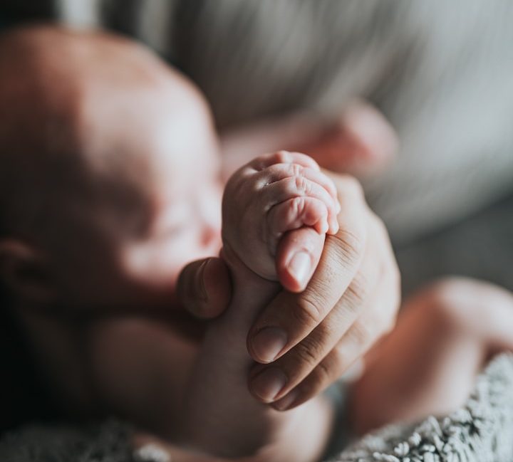 Stillberatung Schlafberatung Beikostberatung in Straubing-Bogen Baby hält Hand von Mama/Papa fest, Hände im Fokus, Baby im Hintergrund. Stillberatung, Schlafberatung, Beikostberatung in Straubing-Bogen